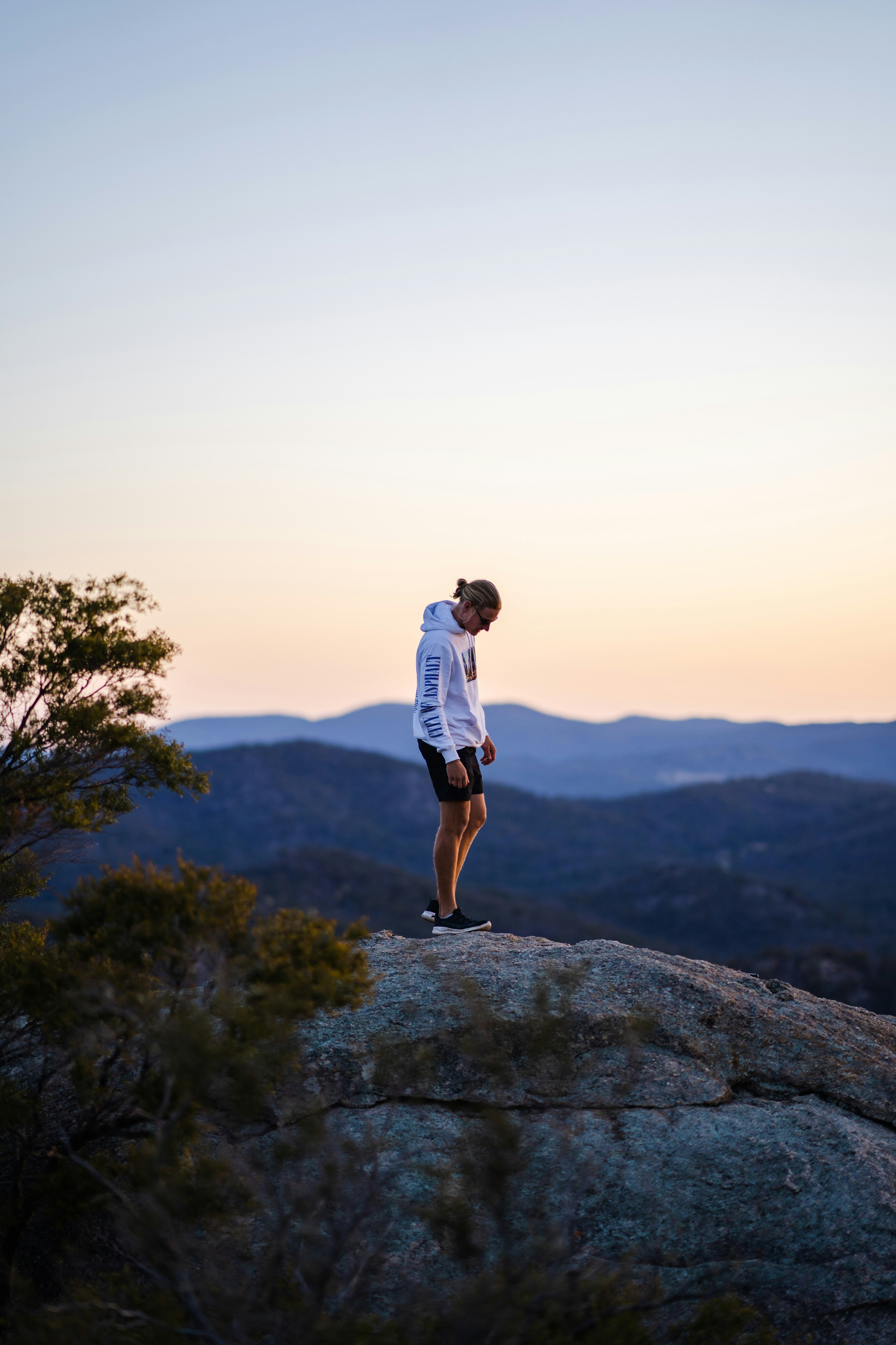 man in white t-shirt and brown shorts standing on rock formation during daytime